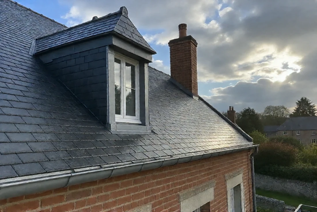 Toit en ardoise propre après nettoyage, maison en brique (Lanobre, Cantal)